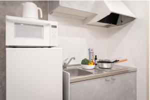 una cucina bianca con lavandino e forno a microonde di MINI HOUSE Tokyo South a Tokyo