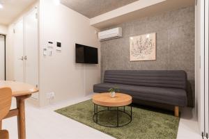ein Wohnzimmer mit einem Sofa und einem Tisch in der Unterkunft MINI HOUSE Tokyo South in Tokio