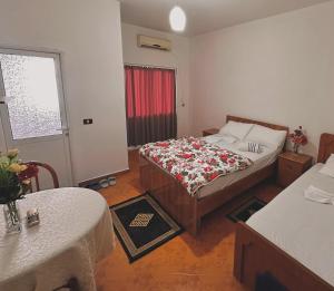 1 dormitorio con cama, mesa y ventana en Hotel Belind en Berat