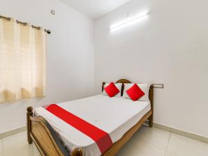 a bedroom with a bed with red and white pillows at OYO Flagship K V R Residency in Yelagiri