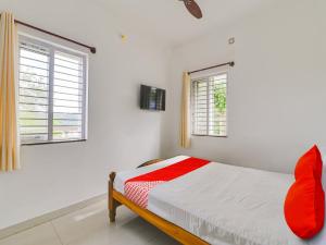 a white bedroom with a bed and two windows at OYO Flagship K V R Residency in Yelagiri