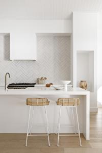 a kitchen with a white counter and two stools at Salt at Shoal Bay in Shoal Bay