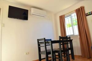 a room with a table and chairs and a television on the wall at Cabañas La Soñada in Chilecito