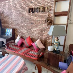 a living room with a couch and a brick wall at Rustic Guest House in Chiang Mai