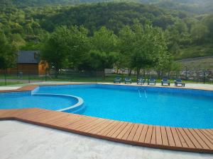 ein großes Schwimmbecken mit Holzterrasse und Bänken in der Unterkunft Camping Prado Verde in Vilamós