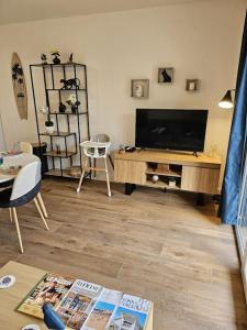 a living room with a flat screen tv and a table at Appartement élégant et bien situé in Biscarrosse