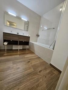uma casa de banho com uma banheira, um lavatório e um espelho. em Appartement élégant et bien situé em Biscarrosse
