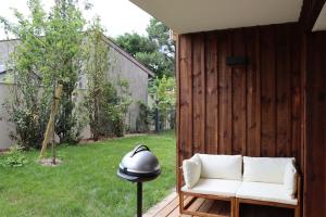 a white couch and a lamp on a patio at Le Cottage Jardin élégant & cosy, plage pour 6 personnes, animaux admis Biscarrosse in Biscarrosse