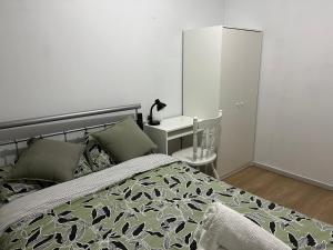 um quarto com uma cama e uma mesa de cabeceira com um candeeiro em double room share bathroom and kitchen em Perth