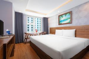 a bedroom with a large white bed and a desk at BIDV Beach Hotel Nha Trang in Nha Trang