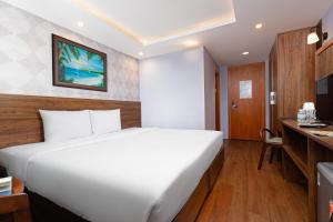 a bedroom with a large white bed and a desk at BIDV Beach Hotel Nha Trang in Nha Trang
