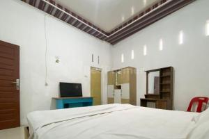 a bedroom with a bed and a tv and a table at Aisyah Homestay Syariah RedPartner in Stabat