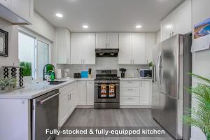 een keuken met witte kasten en een roestvrijstalen koelkast bij Entire Spacious 4-Bedroom House w Free Pool Access, Garage & Parking in Prime Location in San Diego