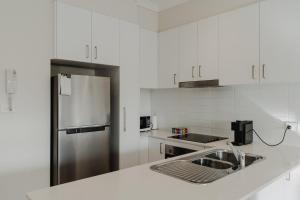 uma cozinha com armários brancos e um frigorífico de aço inoxidável em Cosy 1-Bed In Peaceful Location Across From Park em Camberra