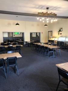 an empty room with tables and chairs and a stage at Cornucopia hotel in Wallaroo