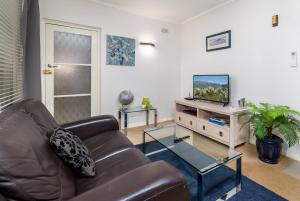 sala de estar con sofá de cuero y TV de pantalla plana en Charming 1-Bed Apartment Near Nature Park, en Campbell