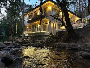 a house on a river with lights on at Arb Pa Home and Cafe @ Mae on in Chiang Mai