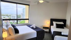 a bedroom with two beds and a large window at Surfers Hawaiian Holiday Apartments in Gold Coast