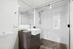 a white bathroom with a sink and a shower at Bright Inner-City 1-Bed with Spacious Balcony in Brisbane