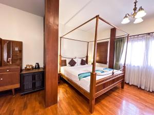 a bedroom with a canopy bed and a wooden floor at Rustic River Boutique in Chiang Mai
