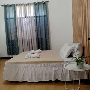 a bedroom with a bed and a table and a window at HOST HOMES - CASA ELIZA in Tacloban