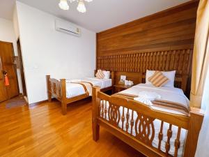 two beds in a room with wooden floors at Rustic River Boutique in Chiang Mai