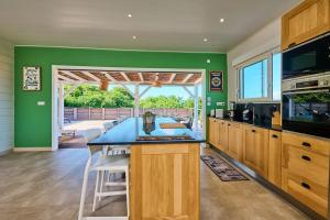 a kitchen with green walls and a table and chairs at villa faula in Le Vauclin
