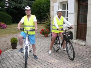 two people in yellow vests riding bikes outside a house at Maison de caractère avec jardin, climatisation et vélos près d'Amboise - FR-1-381-357 in Cangey