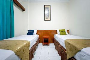 een kamer met twee bedden en een tafel erin bij Urbanview Hotel Pasah Asi Gubeng by RedDoorz in Surabaya