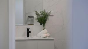 a bathroom sink with a plant in a vase on it at Ravello in Callala Bay +18 photos