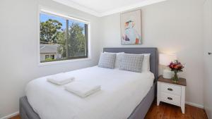 a bedroom with a large white bed with a window at Ravello in Callala Bay