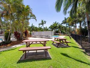 two picnic tables in a park with palm trees at NRMA Capricorn Yeppoon Holiday Park in Yeppoon