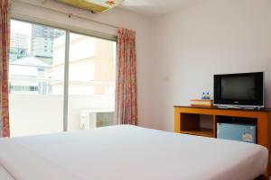 a bedroom with a bed and a tv and a window at Eastiny Bella Vista Hotel in Pattaya