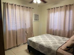 a bedroom with a bed and curtains in a room at Acogedora casa en Alto Boquete, Las Trancas 1 in Boquete