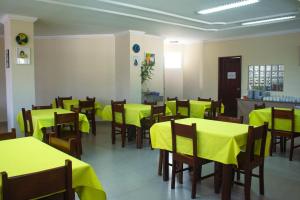 una sala da pranzo con tavoli gialli e sedie in legno di Hotel New Tokyo a Capitão Poço
