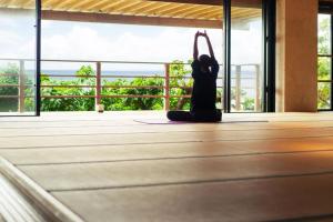 una mujer haciendo una pose de yoga en una habitación con ventana en Hyakunagaran, en Nanjō