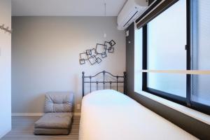 a bedroom with a bed and a chair next to a window at HJ PLACE TAKANAWA in Tokyo