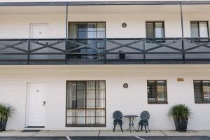 a white building with two chairs and a table on a balcony at Centralpoint Motel in Wagga Wagga