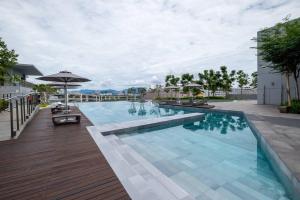 una grande piscina con terrazza in legno e ombrellone di Twinkle Star Kids Room 10pax MyTown IKEA TRX a Kuala Lumpur