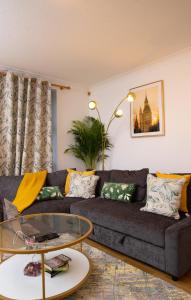 uma sala de estar com um sofá e uma mesa de vidro em The Green Lodge (Bush Hill Park) em Enfield
