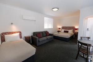 a hotel room with two beds and a couch at Centralpoint Motel in Wagga Wagga