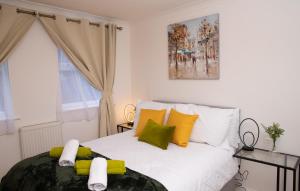 um quarto com uma cama com almofadas amarelas e verdes em The Green Lodge (Bush Hill Park) em Enfield