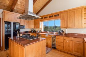 a kitchen with wooden cabinets and a stove top oven at Unmatched Ocean Beach and Mountain Views Family-Friendly Retreat in Moss Beach +49 photos