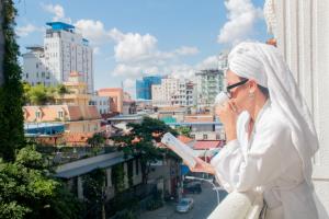 una mujer hablando por celular mientras mira una ciudad en Grand Elevation Hotel en Phnom Penh