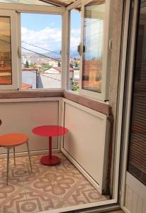 a balcony with a red table and two stools at Una Maria rooms in Podgorica