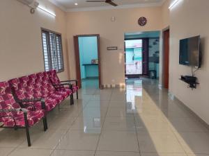 a waiting room with red chairs and a flat screen tv at Thirunallar Ganesha's HomeStay in Karaikal