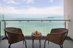 two chairs and a table in front of a large window at Asteria Comodo Nha Trang Hotel in Nha Trang