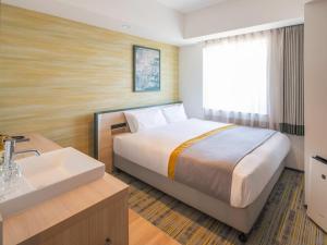 um quarto de hotel com uma cama e um lavatório em La'gent Stay Shin Sapporo em Sapporo