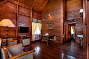 ein Wohnzimmer mit Holzwänden, einem Tisch und einem TV in der Unterkunft Citra Cikopo Hotel & Family Cottages in Puncak