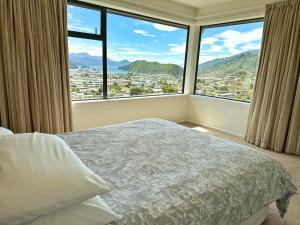 a bedroom with a bed and two large windows at Picton Hilltop Apartment in Picton